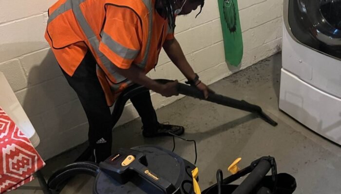 Worker performing water removal and damage restoration with vacuum equipment