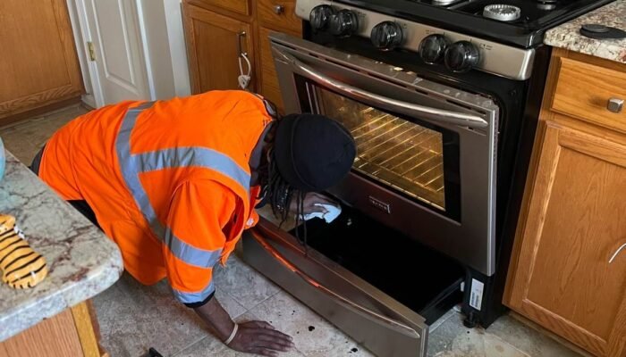 Professional house cleaning worker scrubbing and sanitizing kitchen oven
